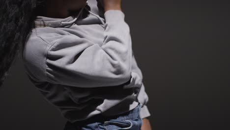 retrato de estudio de una mujer joven con capucha bailando con poca iluminación contra un fondo negro 3