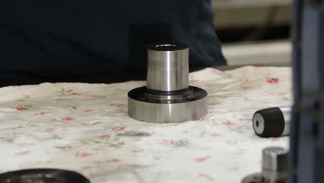 close up of technician hands measuring a metal product with precision caliber micrometer on workshop table