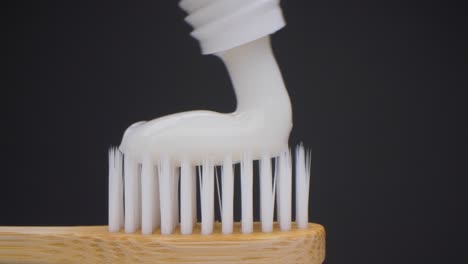 súper primer plano de la cámara de pasta de dientes cayendo sobre el cepillo de dientes