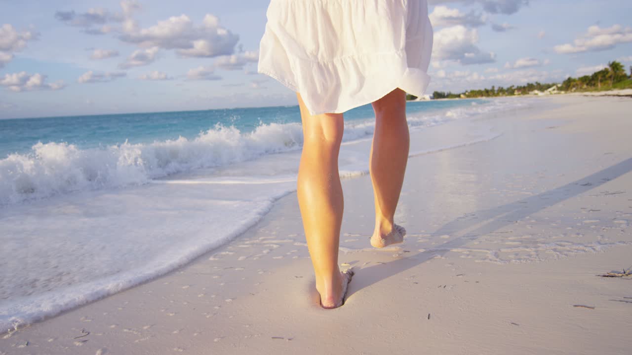 Giovane donna caucasica che cammina a piedi nudi sulla spiaggia