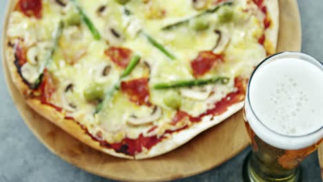 una deliciosa pizza con un vaso de cerveza