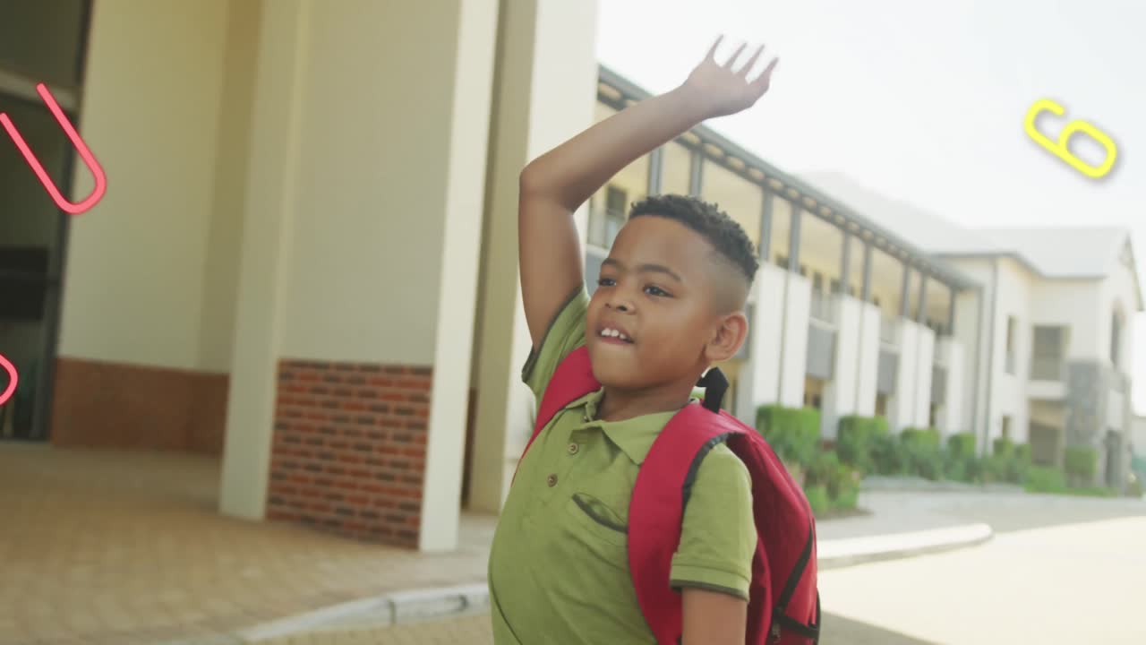 Animation of numbers and letters over happy biracial schoolboy waving outside school