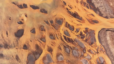 breathtaking aerial drone view of gelber fluss (þjórsá river) in iceland, vibrant orange and black river patterns, surreal landscape.