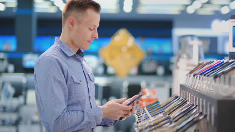 Man-trying-out-new-smart-phone.-Tech-store-interior.