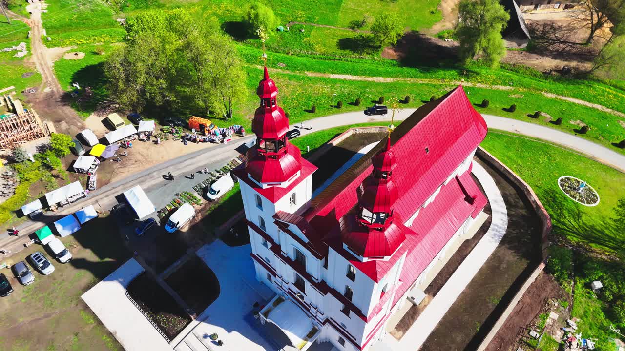 Aerial drone flyover of historic Catholic church in rural Lithuania countryside at sunrise