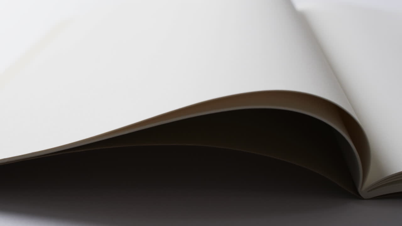 Primo piano di un libro bianco aperto con spazio per il testo su sfondo bianco al rallentatore