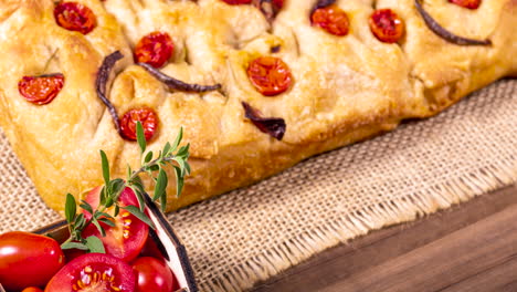 traditional italian focaccia with cherry tomatoes, black olives and rosemary