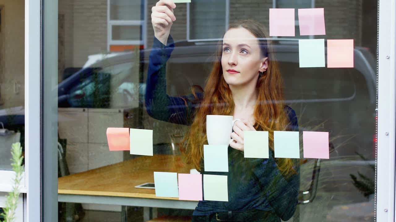 Business executive reading at sticky note while having cup of coffee