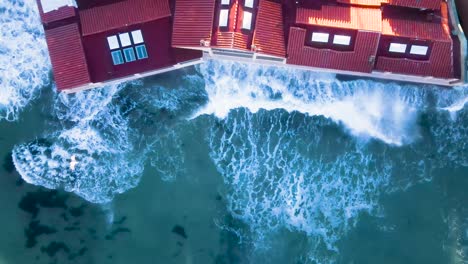 aerial of waves crashing into an oceanfront home