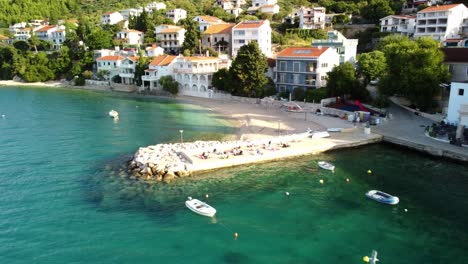 tourists on concrete pier with boats floating in brist village, dalmatia, croatia