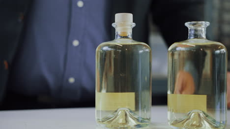 male expert putting a cap on a glass bottle of distilled gin, quality control process in a gin distillery production