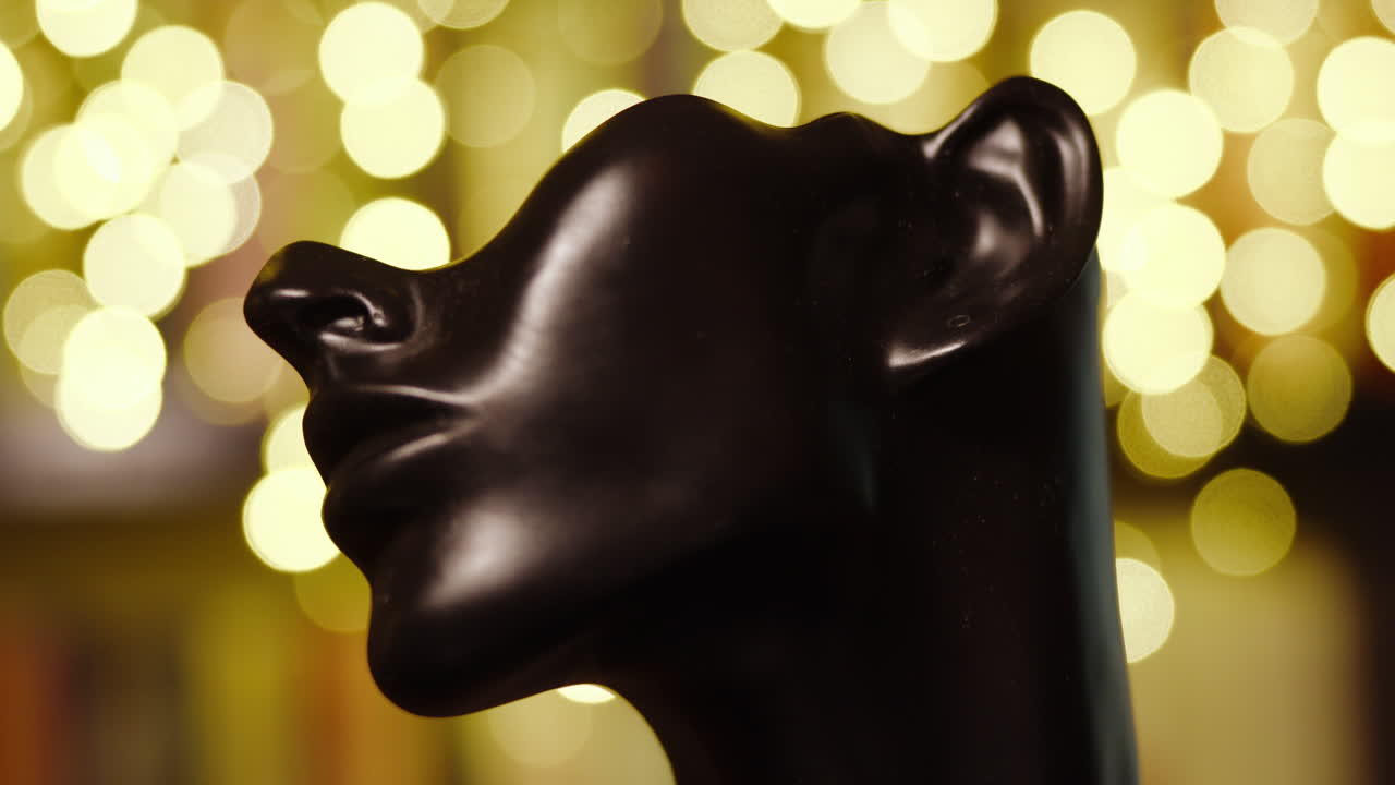 Beaded earring carefully place in the ear lobe of a black mannequin head