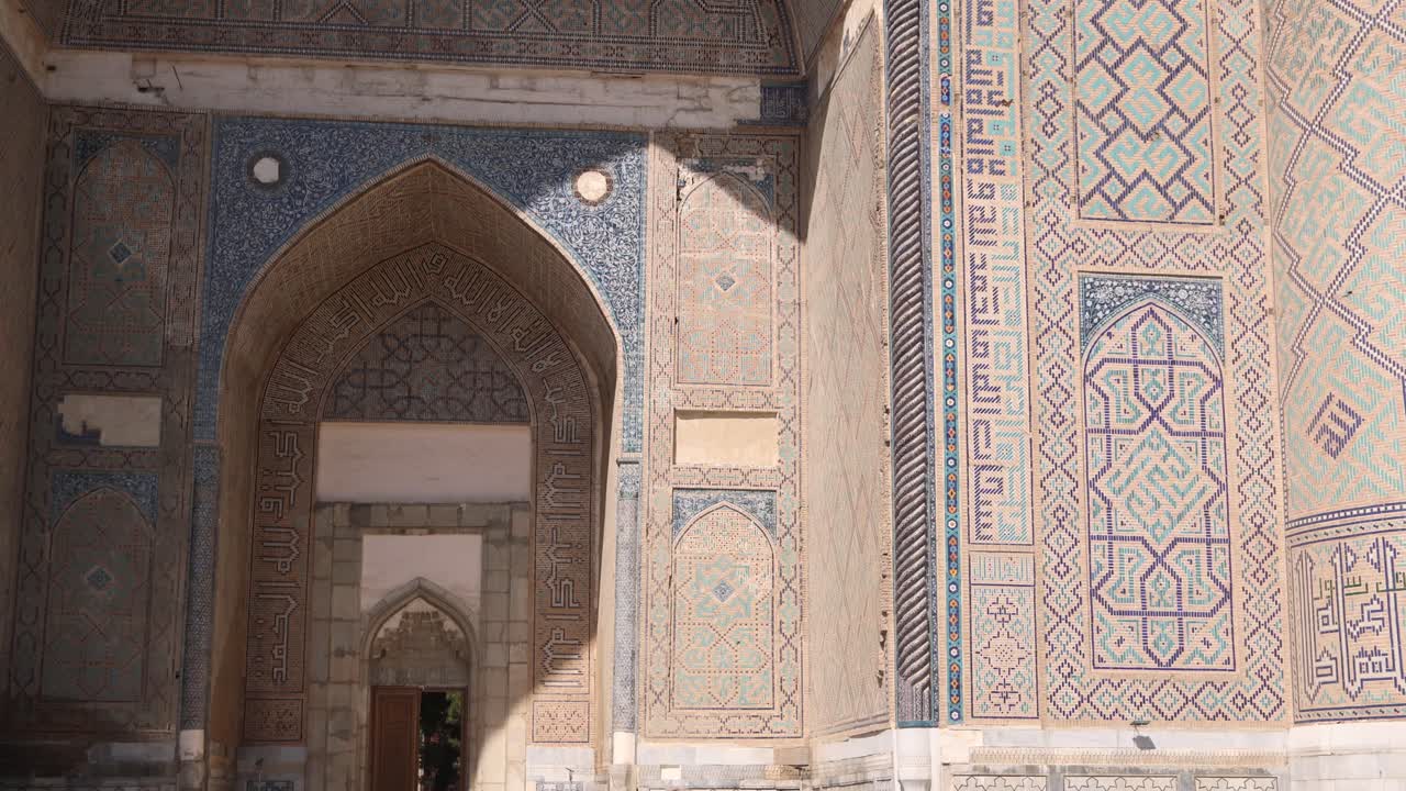 la luz del sol brillante golpeando los azulejos islámicos y las obras de arte en la puerta arqueada en la plaza registan en samarcanda, uzbekistán a lo largo de la histórica ruta de la seda