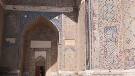 bright sunlight hitting islamic tiling and artwork on arched doorway in registan square in samarkand, uzbekistan along the historic silk road