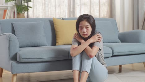 young asian woman victim of violence with bruise on body sits hugging knees and herself being hurt from physically abused at home