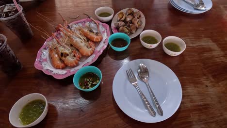 person setting a dining table with seafood dishes