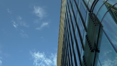 Curved-glass-facade-of-a-modern-skyscraper-against-a-clear-blue-sky