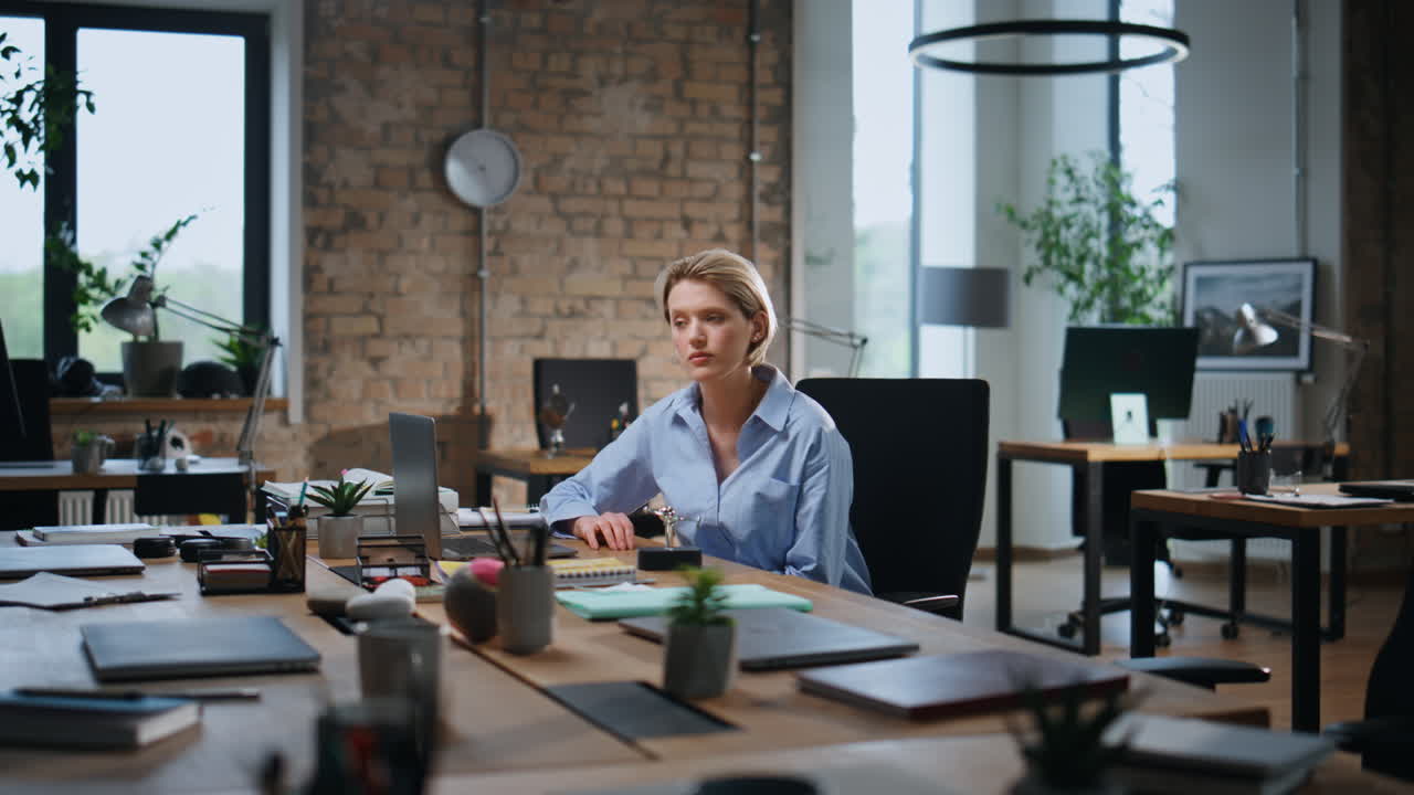 Seria donna d'affari che riflette su una nuova startup seduta in uno spazio di coworking vuoto.