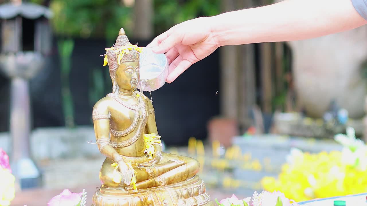 Pouring water over Buddha statue in ceremony