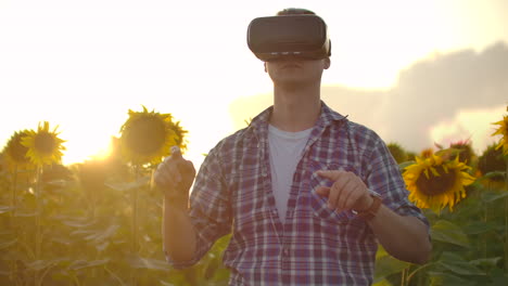 Un-Agricultor-Moderno-Y-Progresista-En-Un-Campo-Con-Girasoles-Utiliza-Tecnología-Vr.-Simulando-La-Interfaz-De-Usuario-De-La-Aplicación.-Controlar-El-Sistema-De-Riego-Con-Drones.-Inspeccionar-El-Campo-Utilizando-Drones.