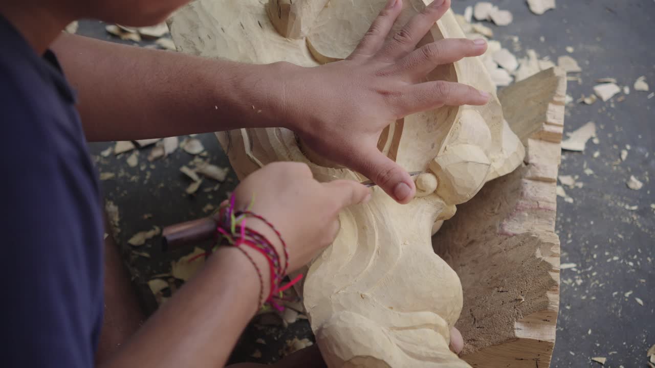 Indonesiano seduto che intaglia e modella una tipica maschera balinese Barong