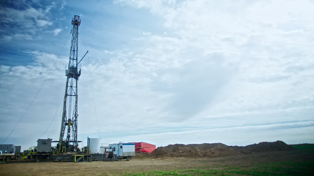 Metal support for oil or gas drilling. Site with machines, equipment and camping caravans. Low angle view.