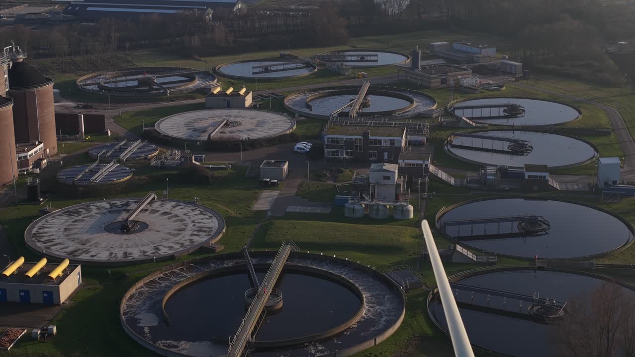 Aerial drone video of a wastewater and sewage treatment plant in Haarlem, Netherlands, showing water purification infrastructure, circular basins, environmental management, and urban sanitation system