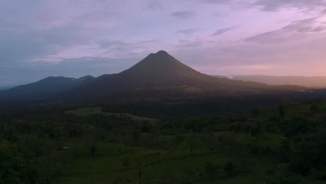 an epic aerial drone shot of the famous arenal volcano in la fortuna, costa rica by sunset