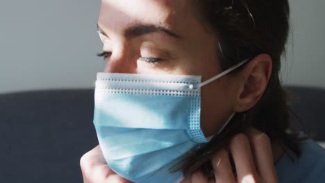doctora caucásica con máscara facial en casa sentada en el sofá