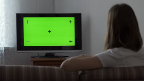 woman sitting on sofa and watching tv with chroma key at home