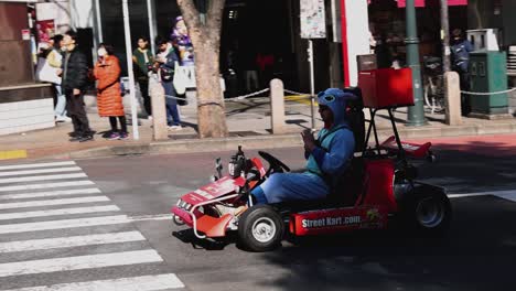 person in costume driving go-kart in city traffic