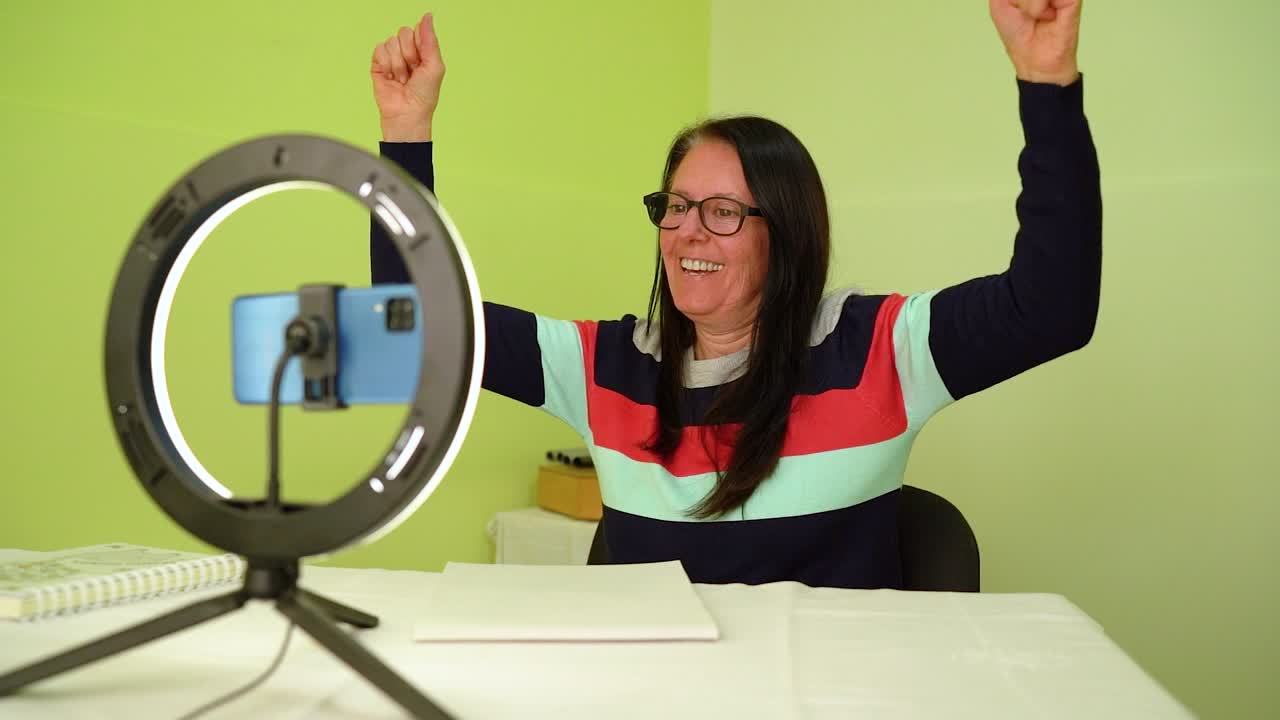 mujer madura frente a su teléfono móvil con expresión exitosa, celebrando - medio