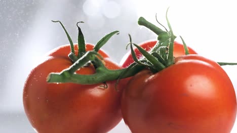 Wasser-Sprüht-Auf-Einen-Haufen-Frischer-Roter-Tomaten,-Die-Sich-In-Zeitlupe-Drehen,-Nahaufnahme