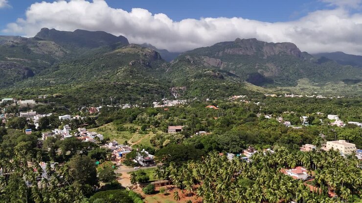 Maestoso panorama aereo dei Ghati occidentali di Courtallam, che mostra una città in una valle boscosa, cascate fluenti e nuvole monsoniche che abbracciano le montagne