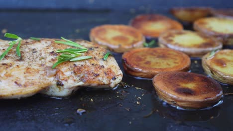 grill pan full of sliced potatoes with chicken meat steak, side closeup view