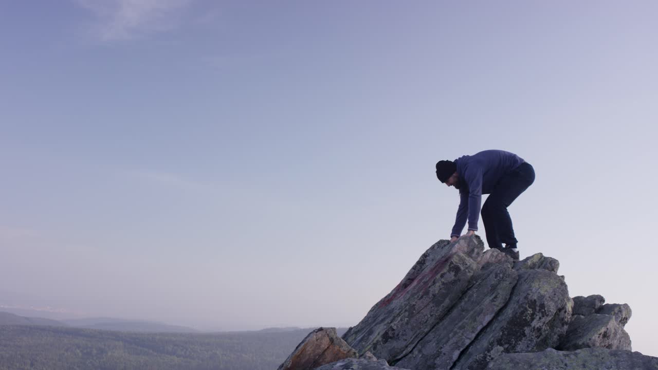 hombre escalando y de pie en el pico de la montaña