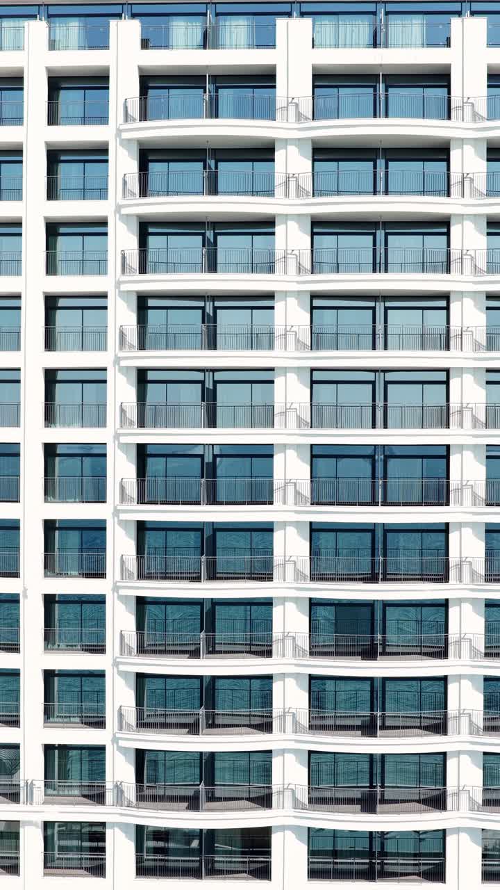 Facciata simmetrica di un grattacielo contemporaneo con balconi ripetuti. Ideale per progetti di design urbano e studi di architettura.