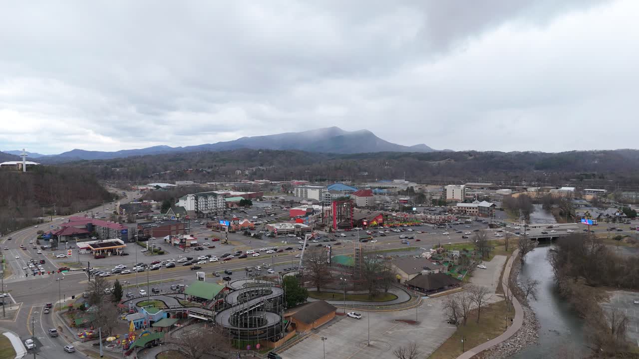 Aerial shot pulling out from Piegon Forge, TN on January 1st 2025 with snow covered Smoky Mountains in the background.