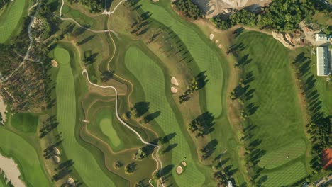 aerial overhead view of a golf course with beautiful abstract patterns, sand traps, trees and lakes