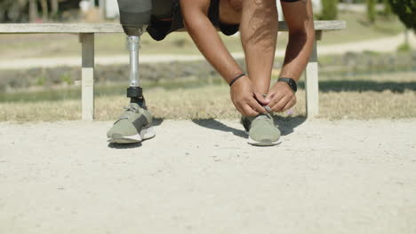 front view of man with bionic leg tying shoelaces before cycling