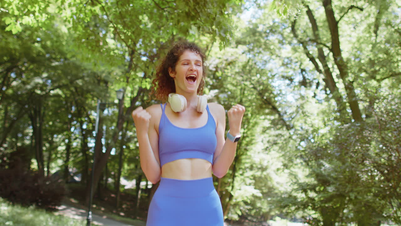 corredora atlética en forma chica celebra el éxito gana grita se regocija triunfo victoria carrera de maratón en el parque