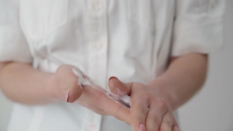 woman taking care of her hand skin by applying foamy cleaner creme, close up view