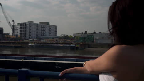 slow motion of a beautiful latina woman on holiday leaning against the railing, looking at the river thames in london, looking at the camera, smiling and wandering around