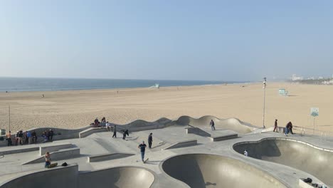 Vista-Aérea-De-Personas-Patinando-En-Venice-Beach-California-Arena-Blanca