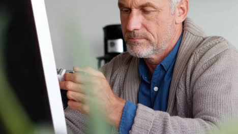 Male-executive-holding-digital-camera-at-desk