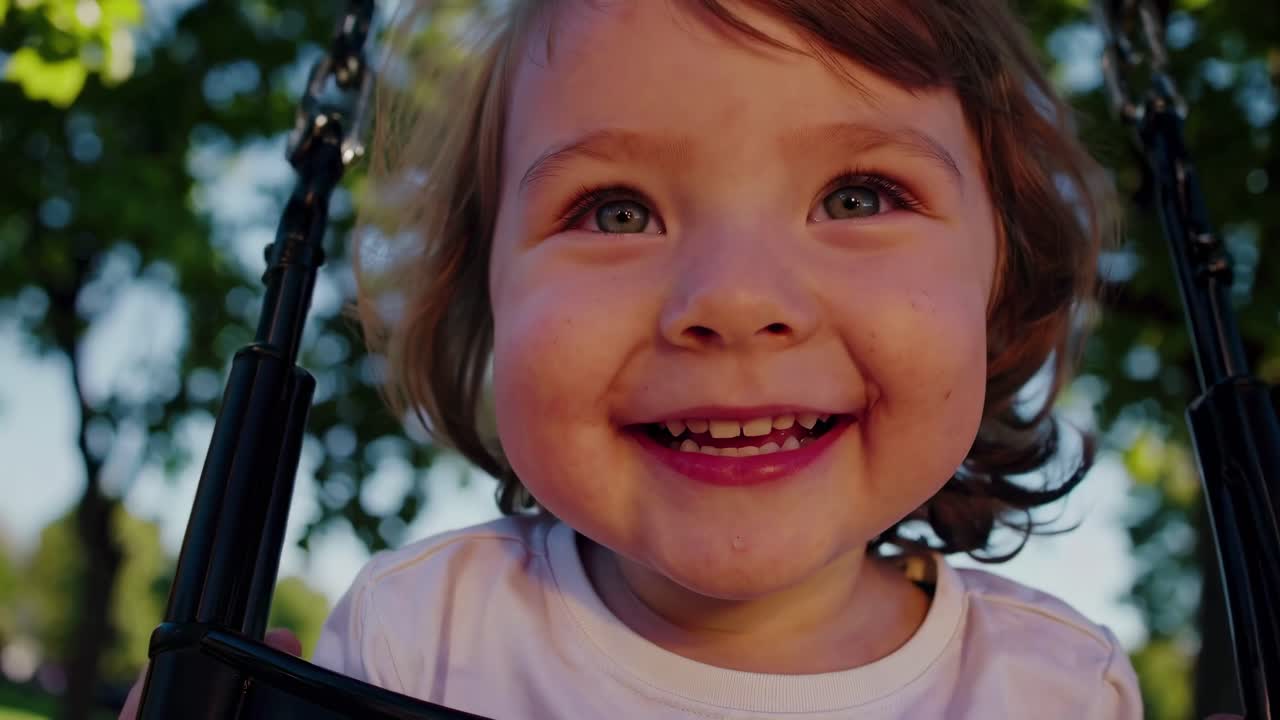 Vídeo em close-up de uma criança alegre em um balanço, capturado de um ângulo baixo