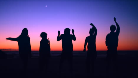 friends dancing at sunset on the beach