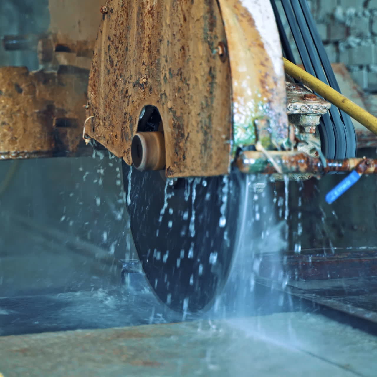 Process of cutting stone slab withautomated machine on the brick wall background. Man in working clothes operates with cnc machine in factory.