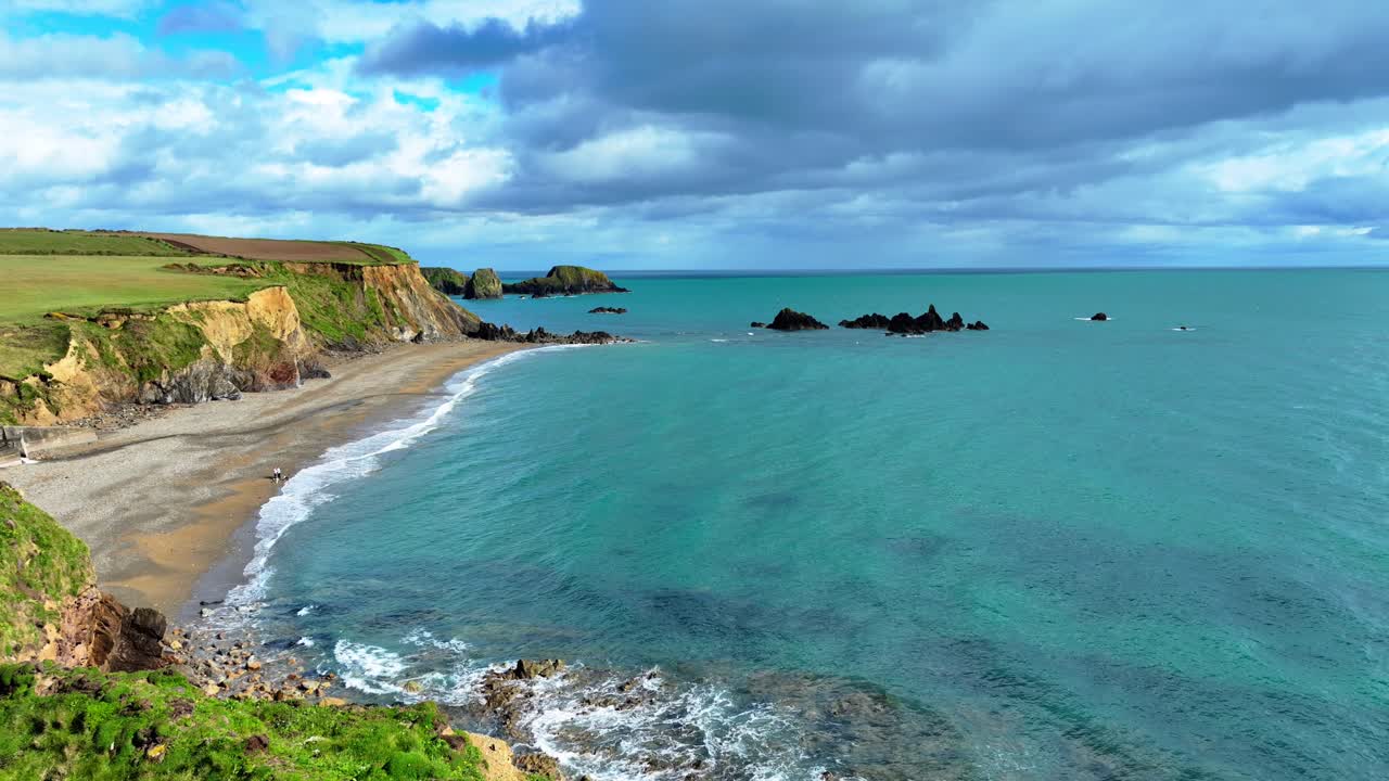 drones volando sobre acantilados marinos personas jugando con perros en el agua colores dramáticos del mar y el horizonte y rocas raras en mares verde esmeralda