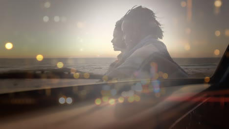 animation of happy african american couple at beach at sunset over cityscape